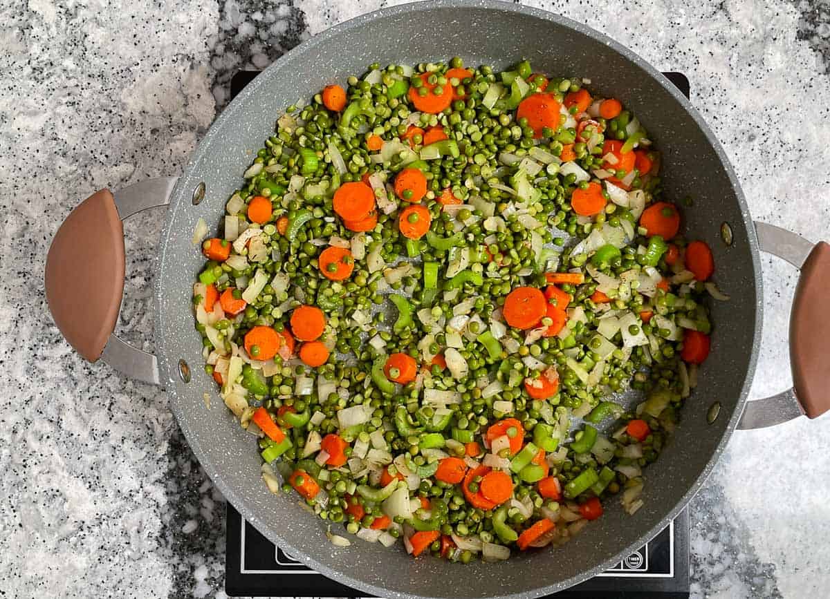 Dried split peas added to pot with onions, carrots, and celery.