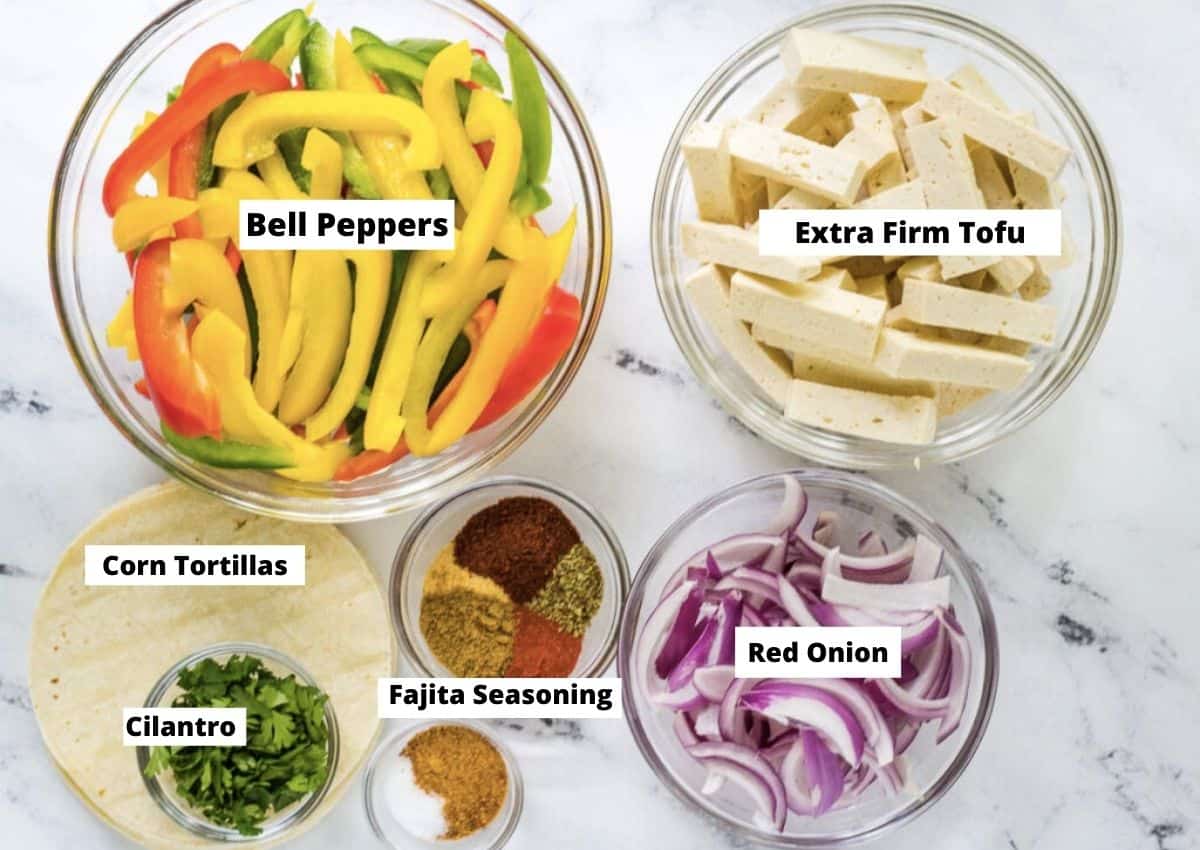 Tofu Fajitas ingredients: sliced bell peppers, tofu, sliced red onion, fajita seasoning, cilantro, corn tortillas. 