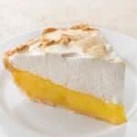 Slice of vegan lemon meringue pie on white plate.