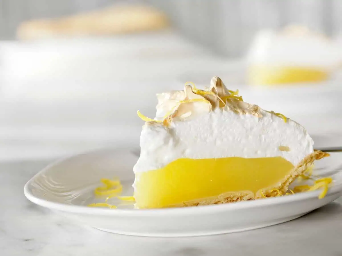 Slice of vegan lemon meringue pie on white plate
