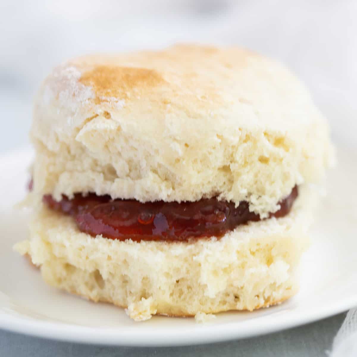 Scone on plate filled with strawberry jam.