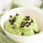 Avocado nice cream in white bowl topped with mini chocolate chips.