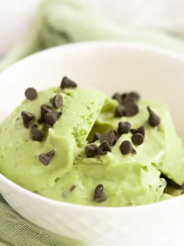 Avocado nice cream in white bowl topped with mini chocolate chips.