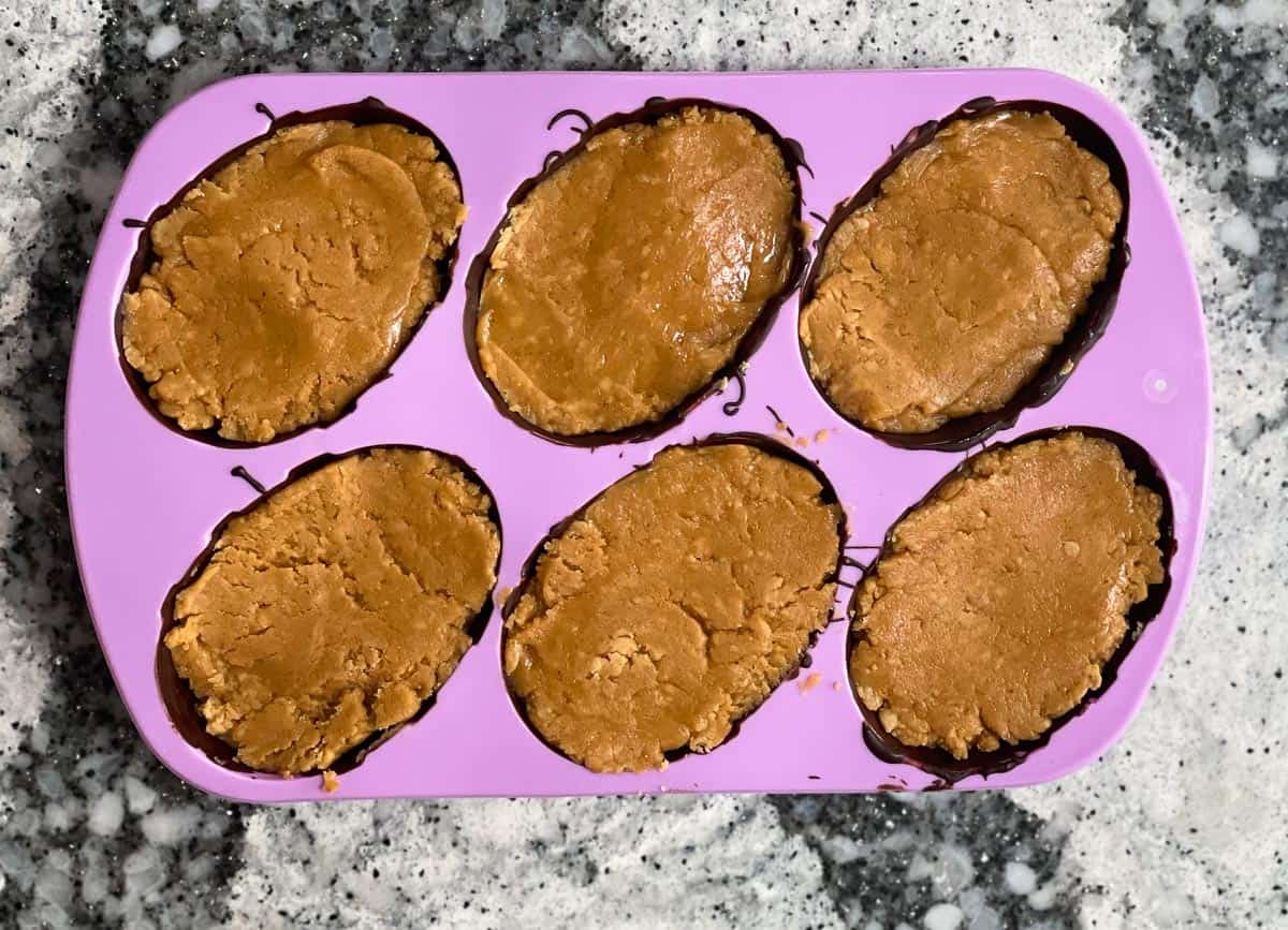 Filling peanut butter dough in chocolate egg mold. 