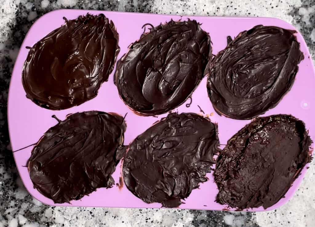 Topping chocolate egg mold with more melted chocolate. 