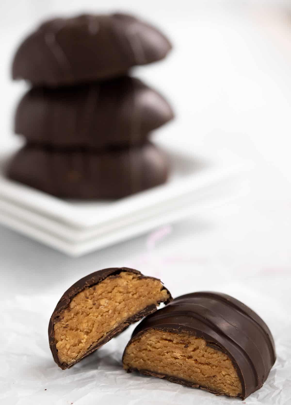 Chocolate peanut butter egg cut in half, with stack of chocolate eggs in the background.