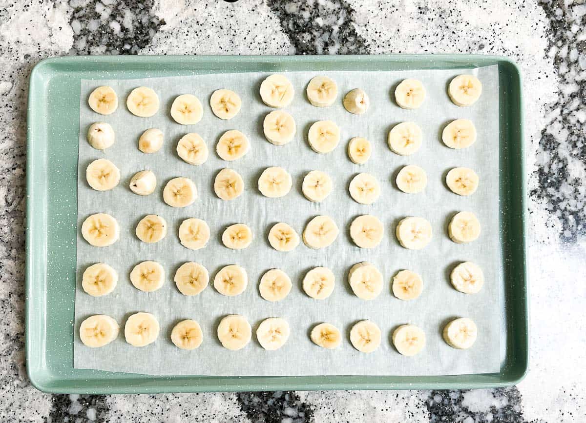 Banana slices on baking sheet lined with parchment paper. 