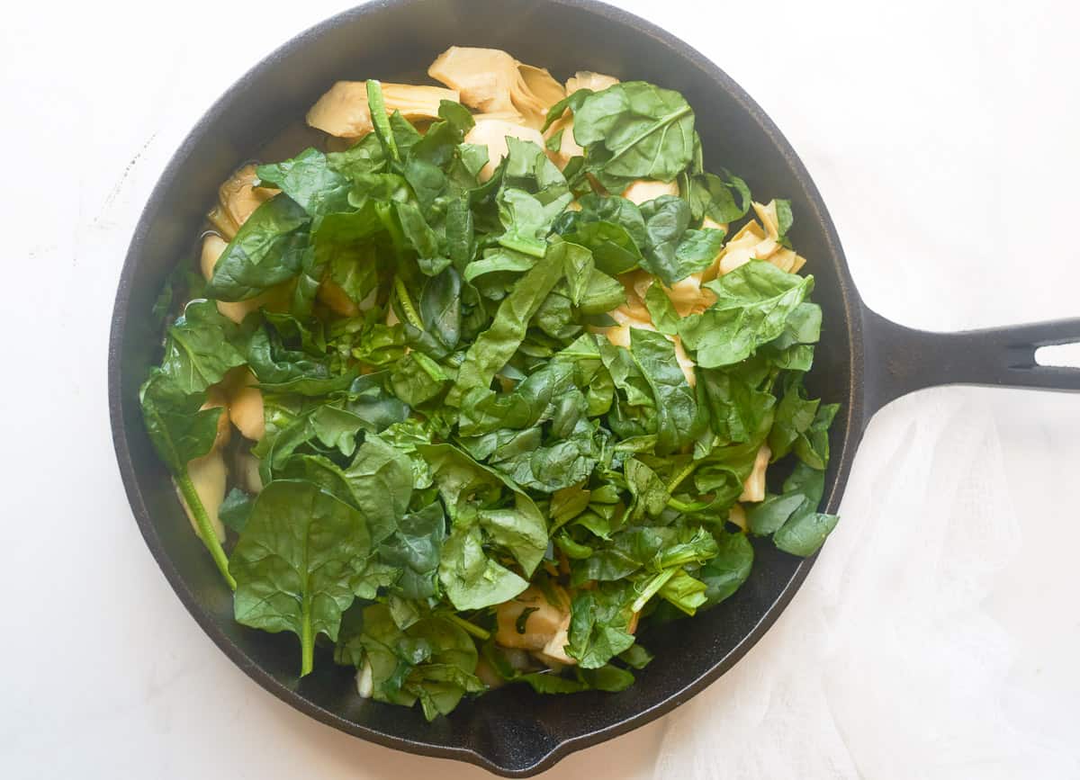 Artichoke hearts and fresh spinach added to skillet.