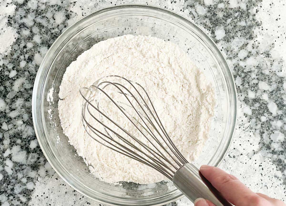 Whisking flour in glass mixing bowl. 