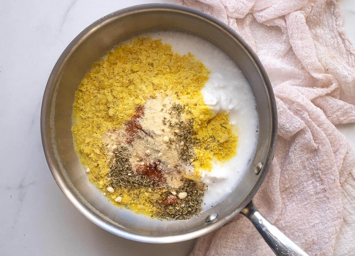 Coconut milk, nutritional yeast, and spices in saucepan. 