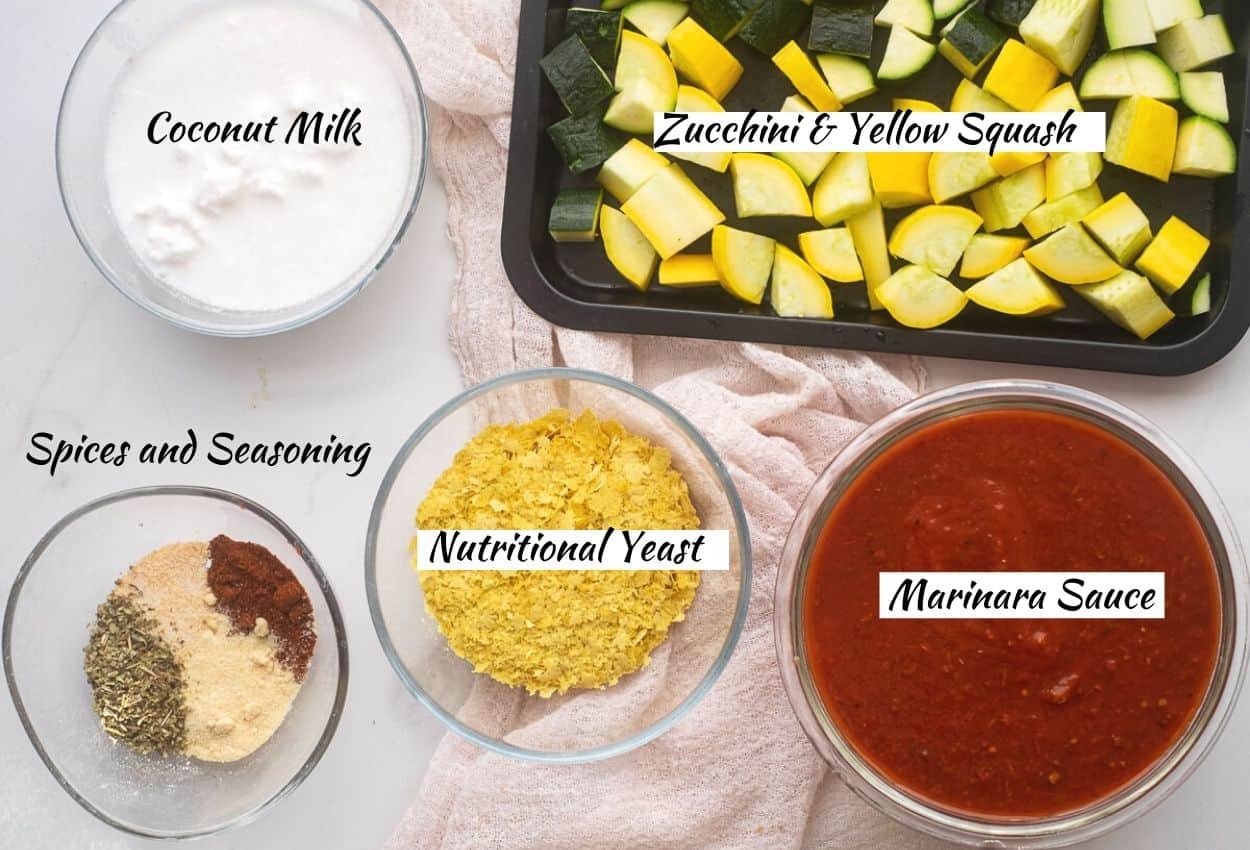 Vegan pasta bake ingredients: coconut milk, spices and seasoning, nutritional yeast, marinara sauce, zucchini and yellow squash. 