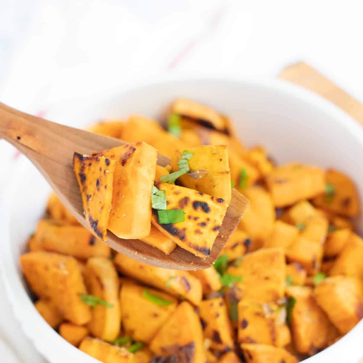 Sweet potato sauce in white bowl on wood spoon. 