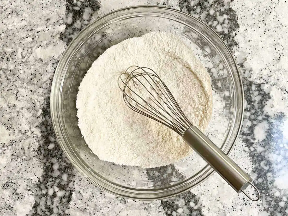 Flour and sugar whisked in glass bowl. 