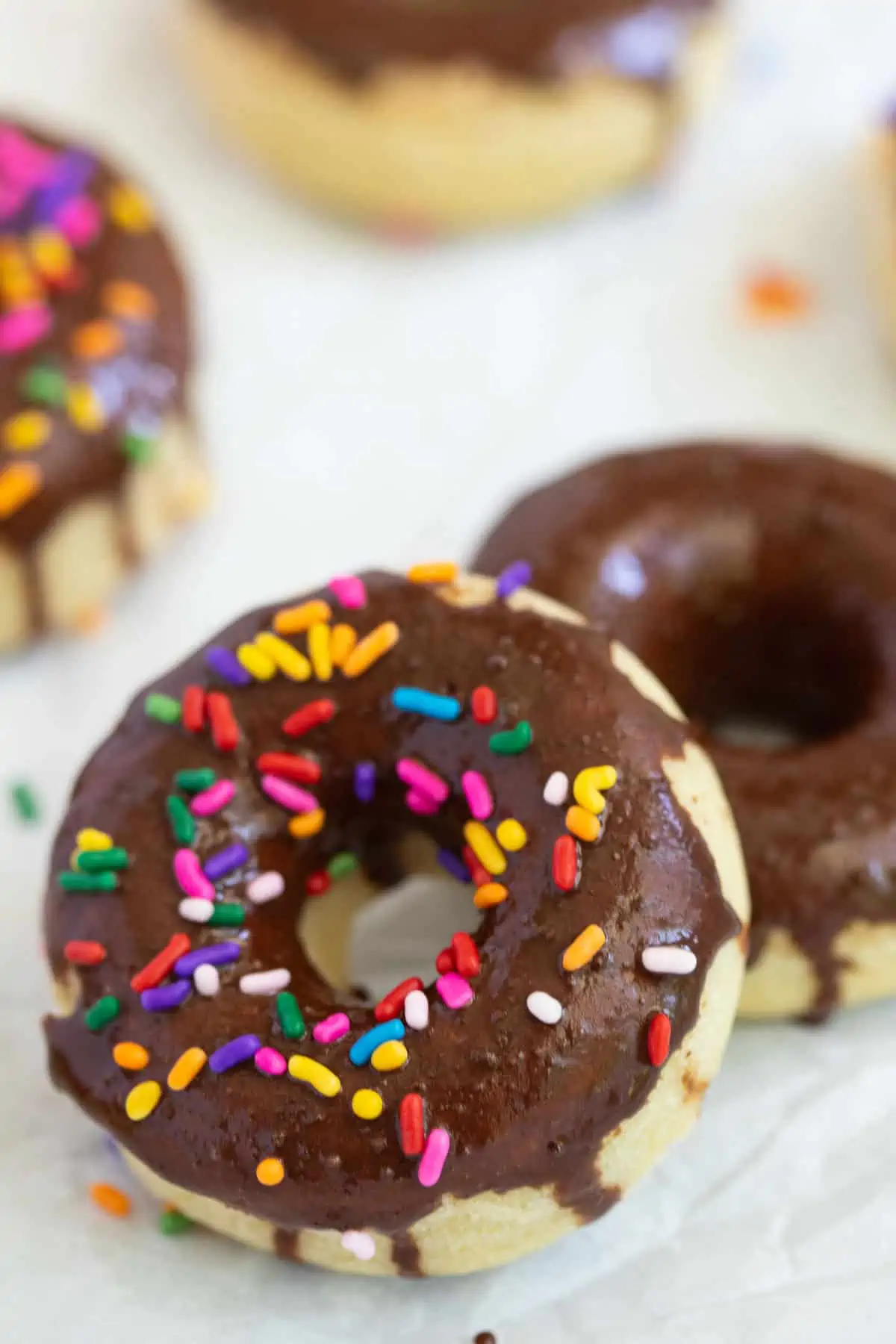 Vanilla donuts topped with chocolate icing and sprinkles. 