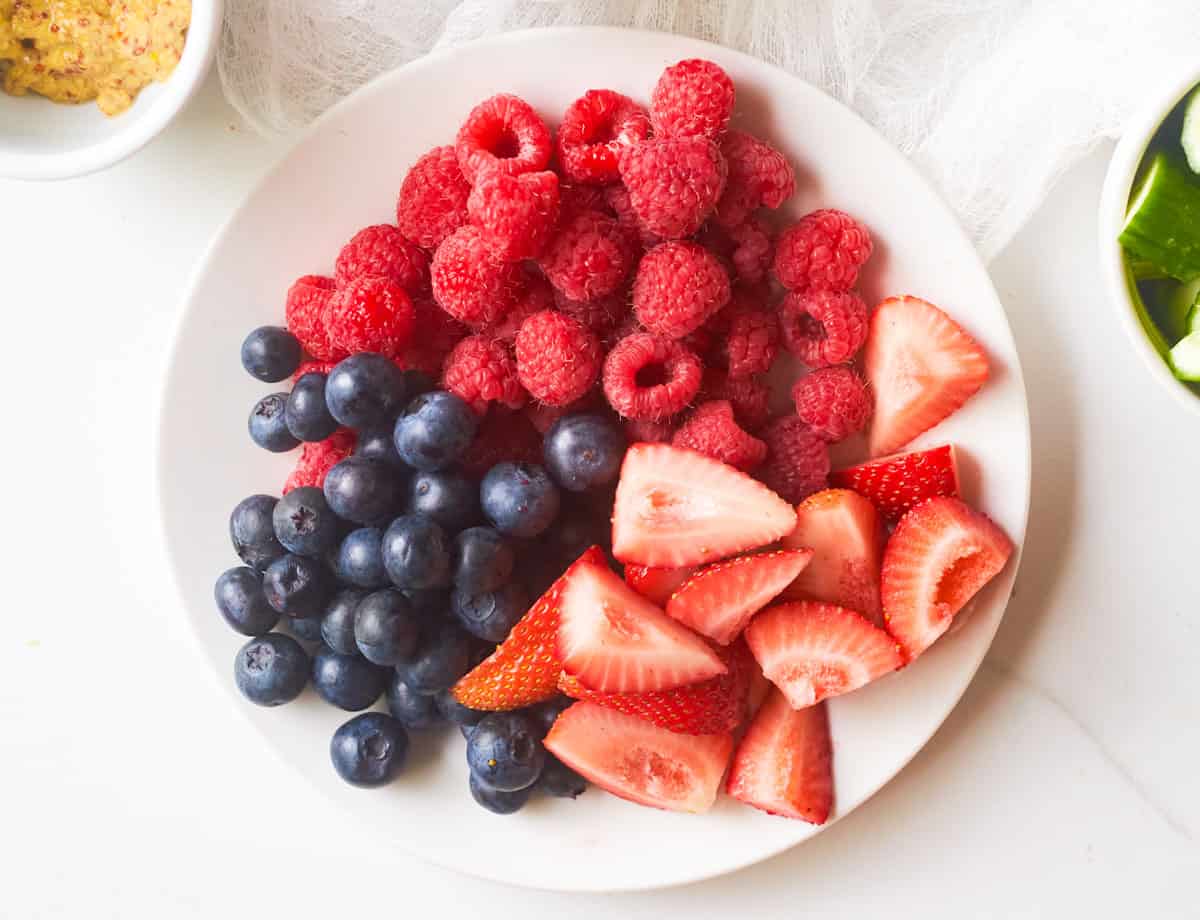 Raspberries, blueberries, and strawberries on plate.
