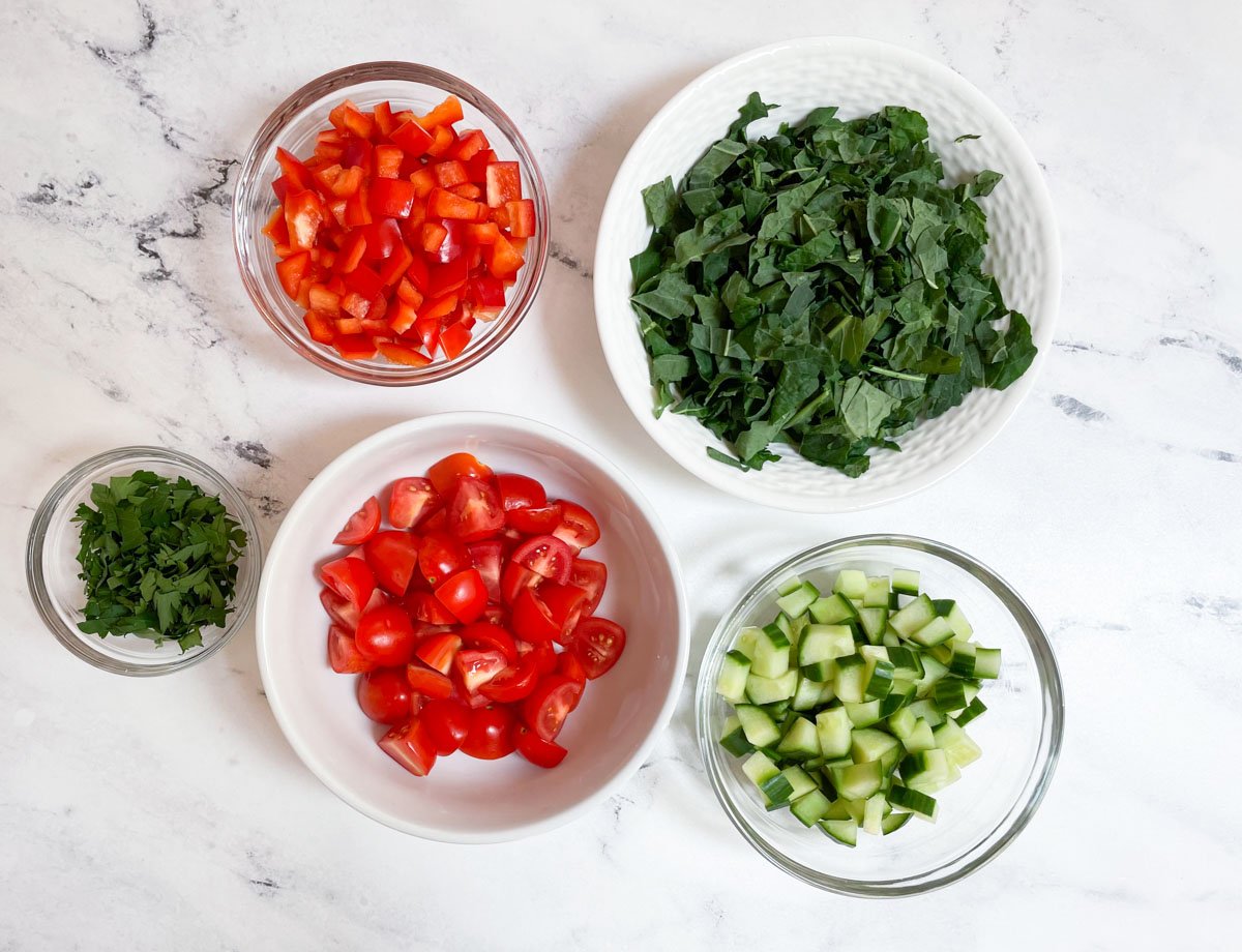 Diced red peppers, diced cucumber, diced cherry tomatoes, chopped kale, and chopped parsley.