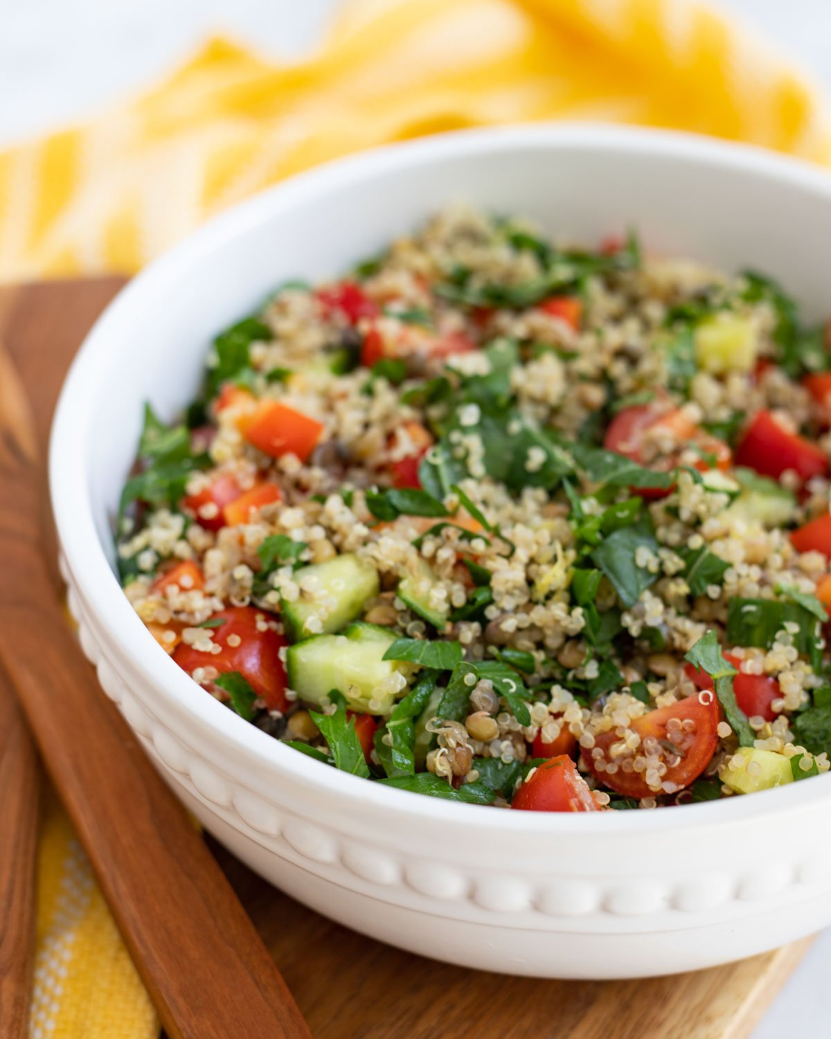 Quinoa, lentil, and vegetable salad in white bowl. 