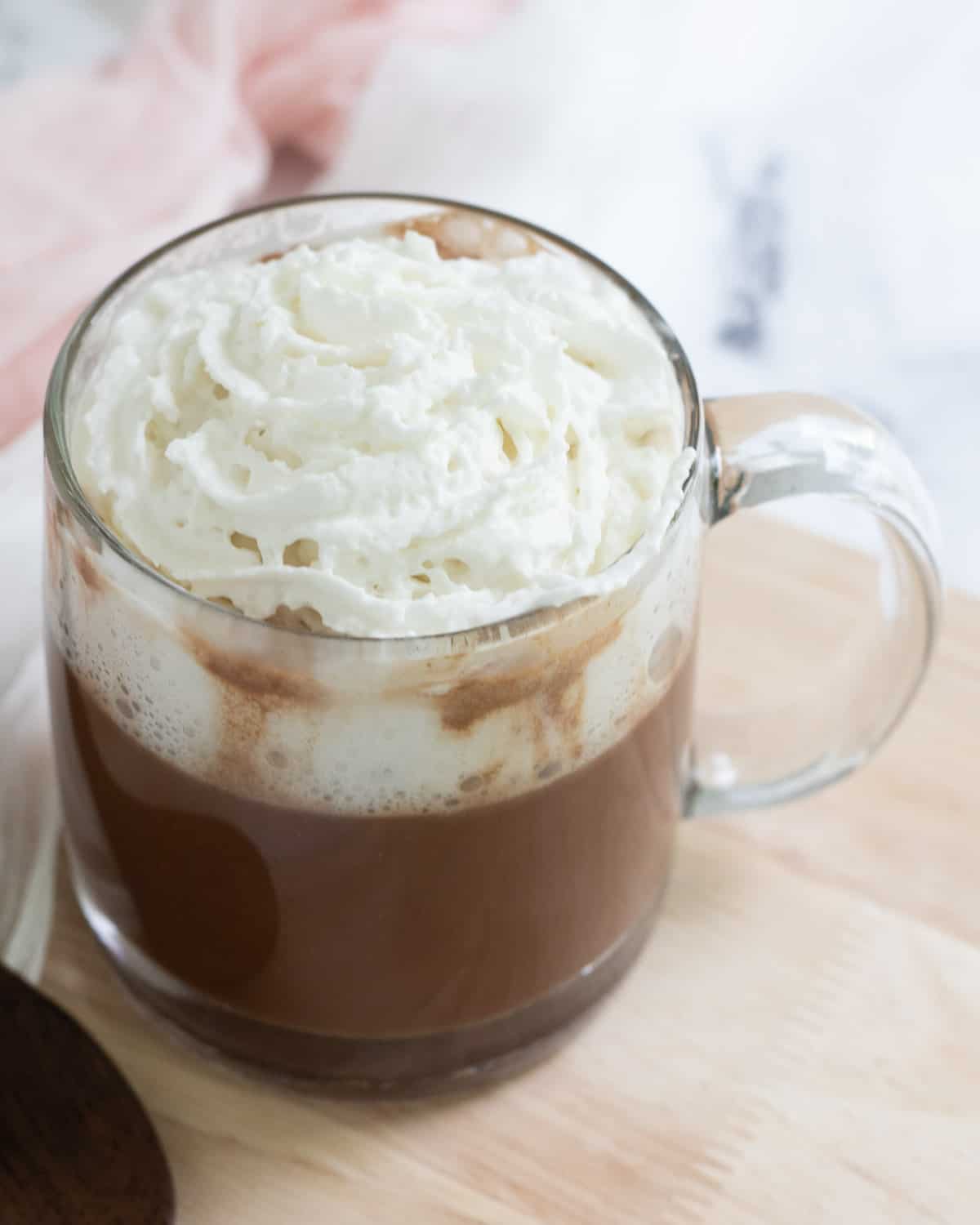 Cup of oat milk hot chocolate topped with coconut whipped cream.