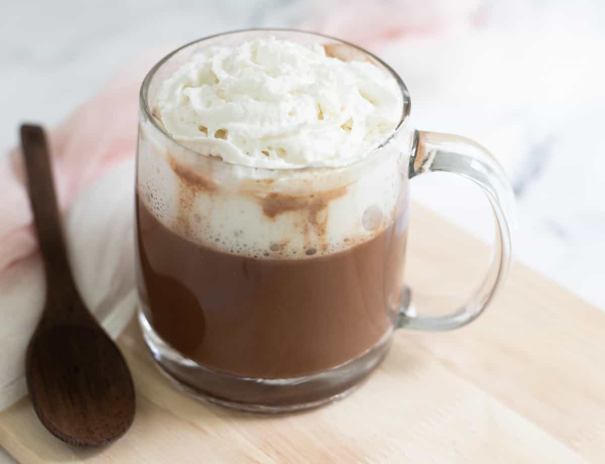 Cup of oat milk hot chocolate topped with coconut whipped cream. 