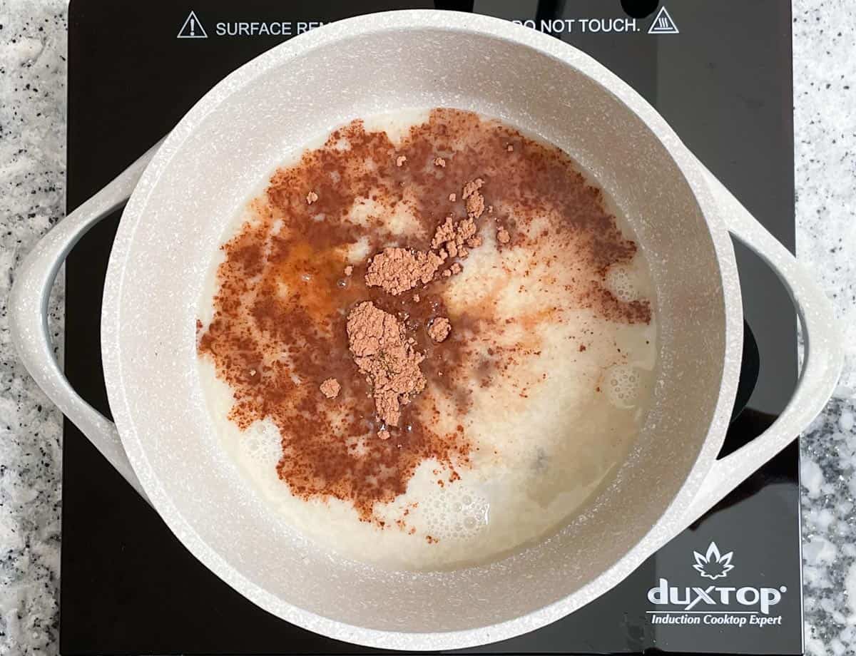 Adding hot chocolate ingredients to pot.