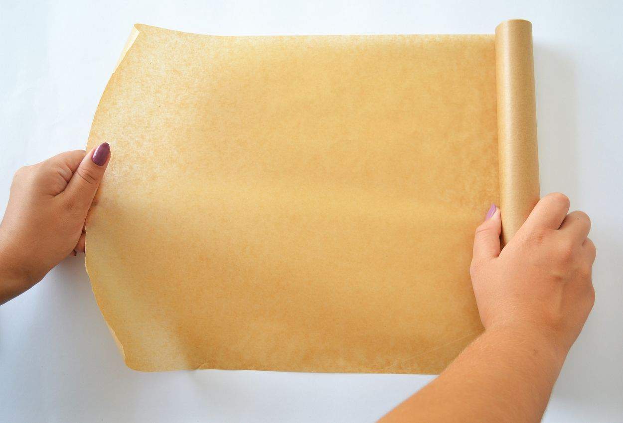 Hands pulling out sheet of brown parchment paper.