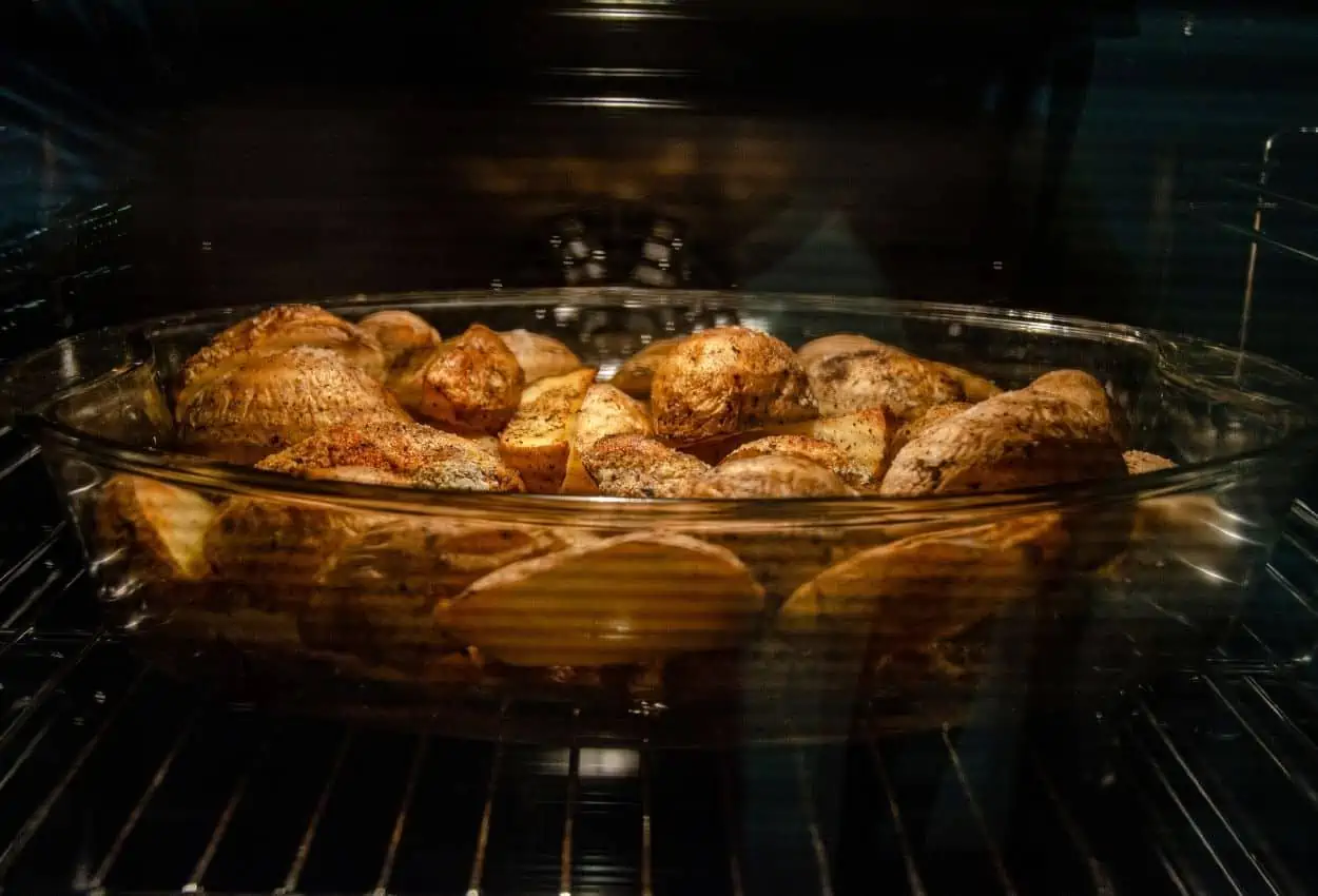 Glass baking dish filled with roasted potatoes in oven.