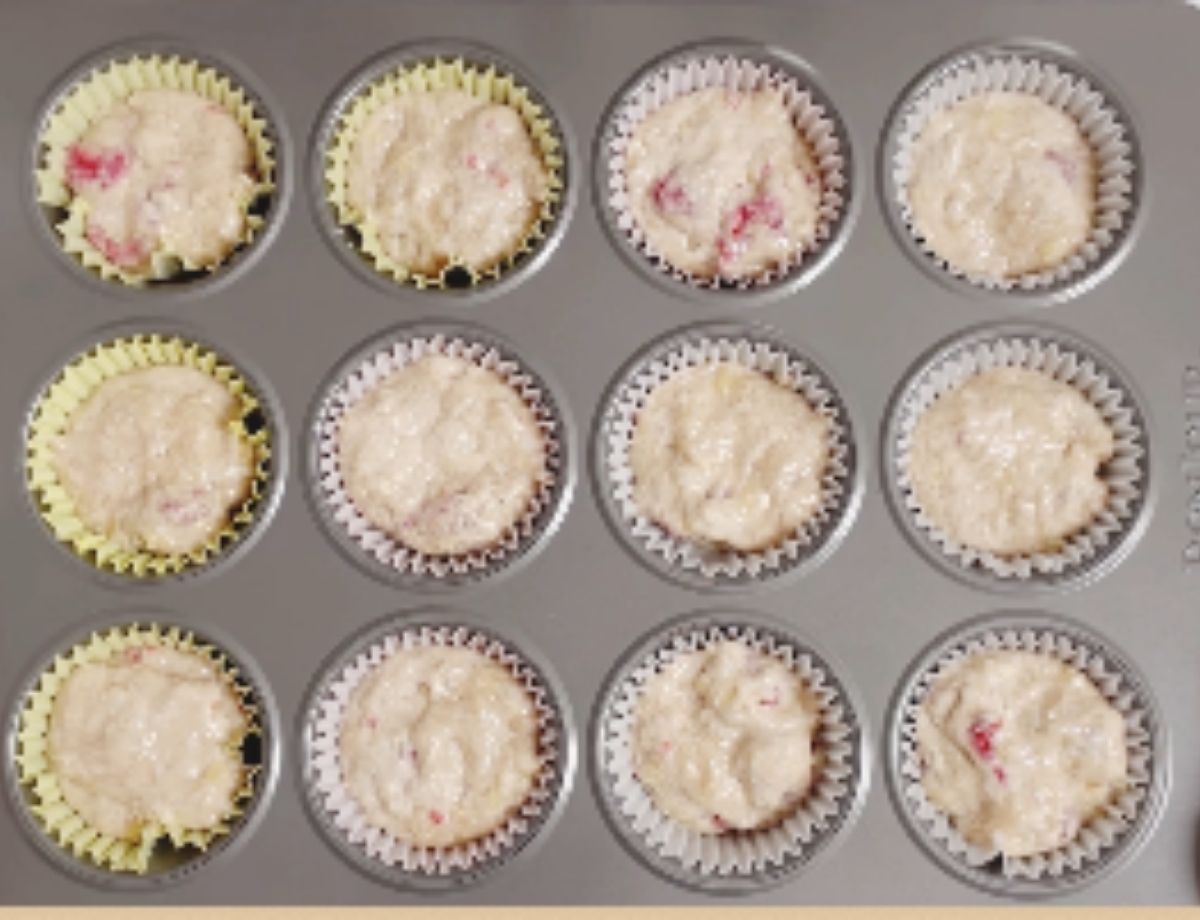 Filling muffin tin with raspberry muffin batter.