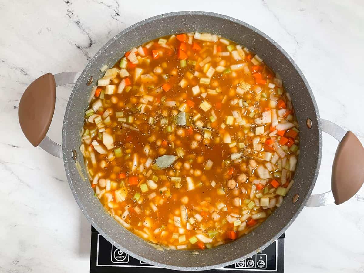 Chickpea soup and spices cooking in pot. 