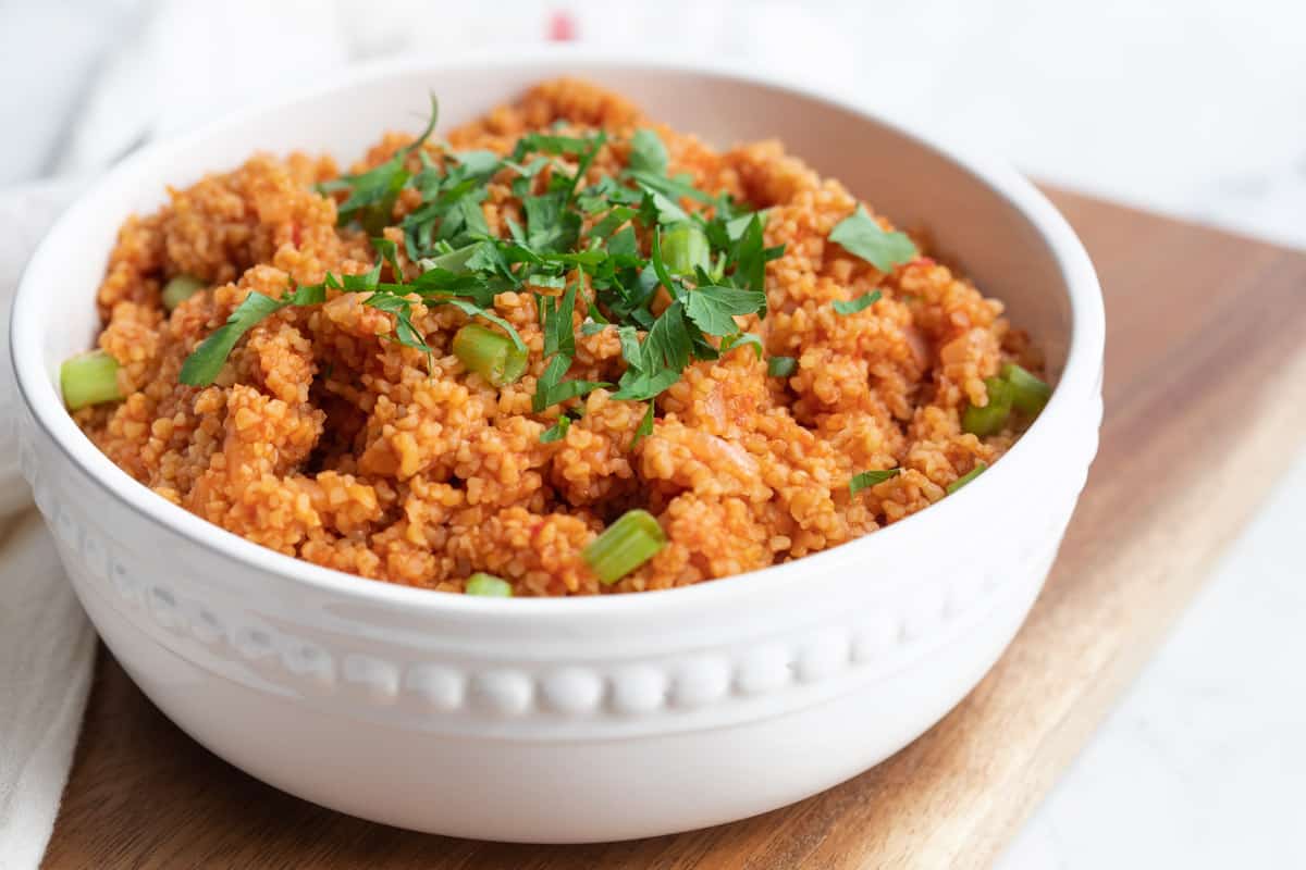 bulgur pilavi topped with fresh parsley and scallions in white serving bowl. 
