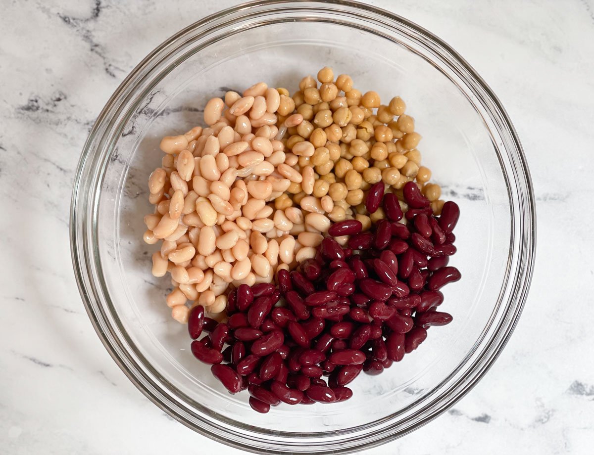 Chickpeas, cannellini beans, and kidney beans in glass bowl. 
