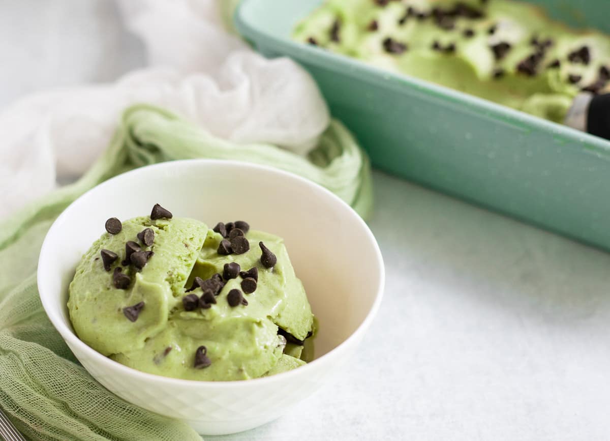 Avocado nice cream in white bowl topped with mini chocolate chips.
