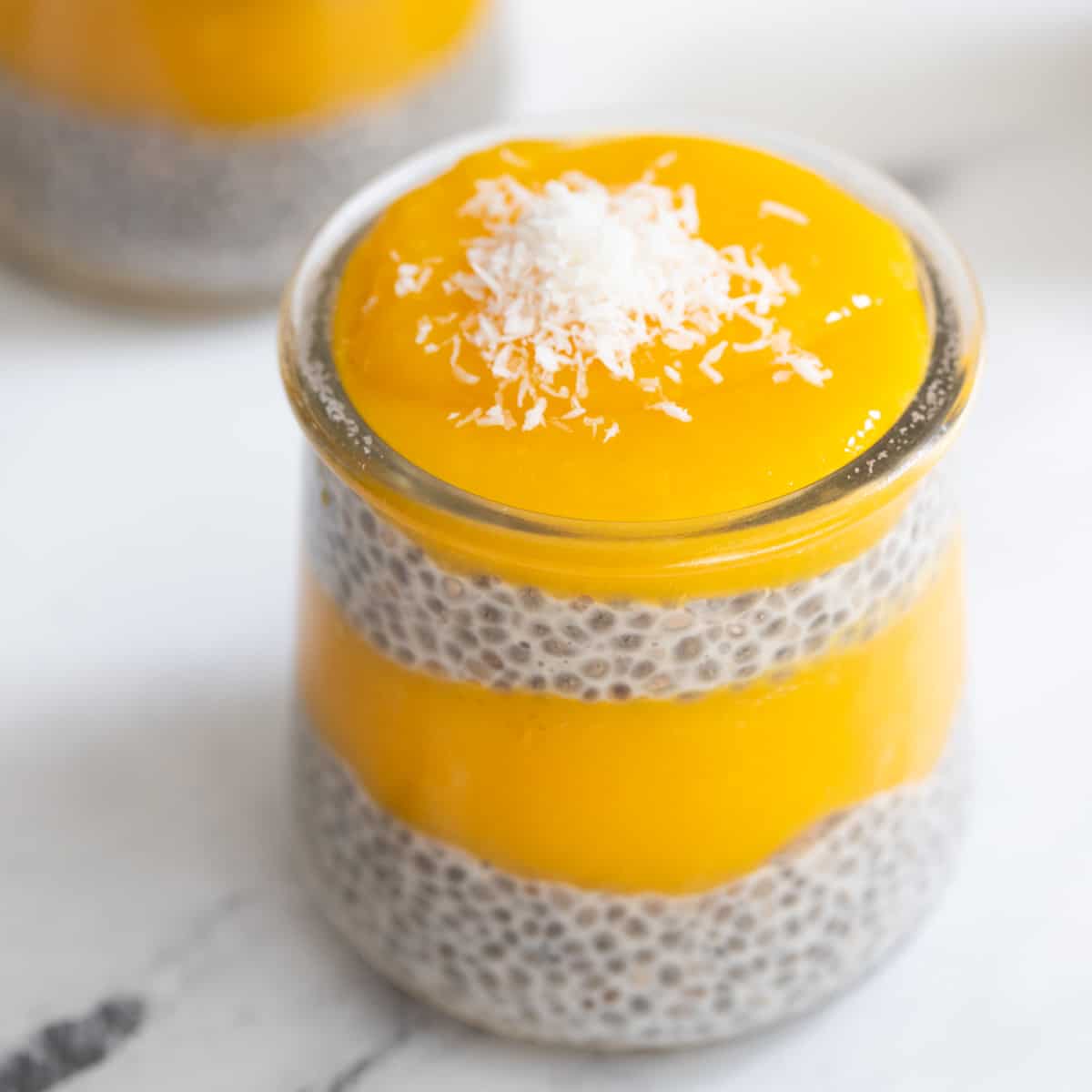 Cup of chia mango pudding. topped with coconut.