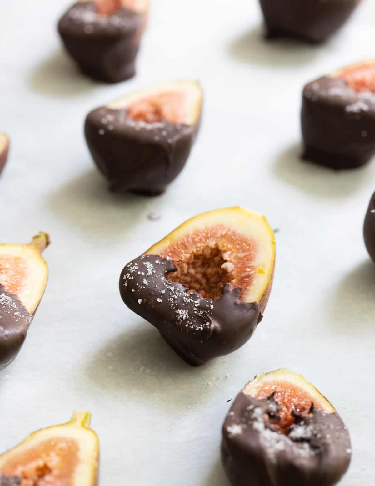 Fig dipped in chocolate on baking sheet lined with parchment paper. 