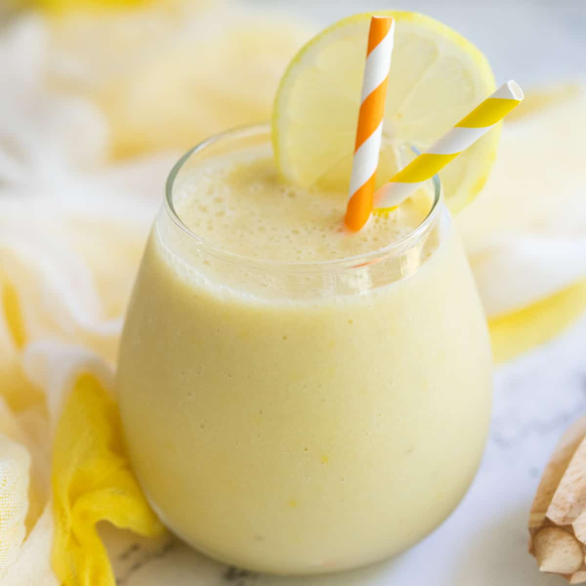 Lemon smoothie in glass served with lemon round.