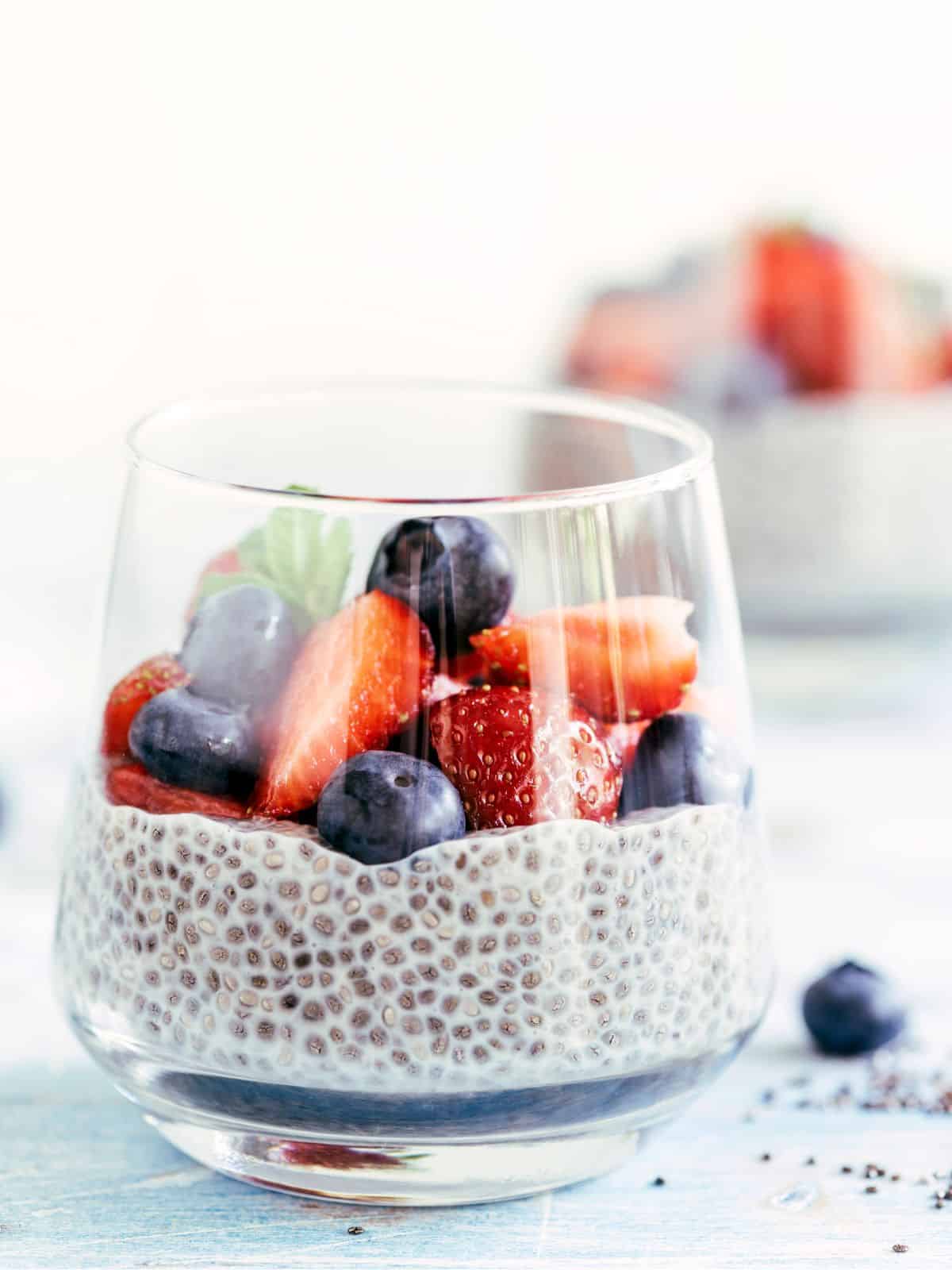 Chia pudding in glass topped with fresh berries. 