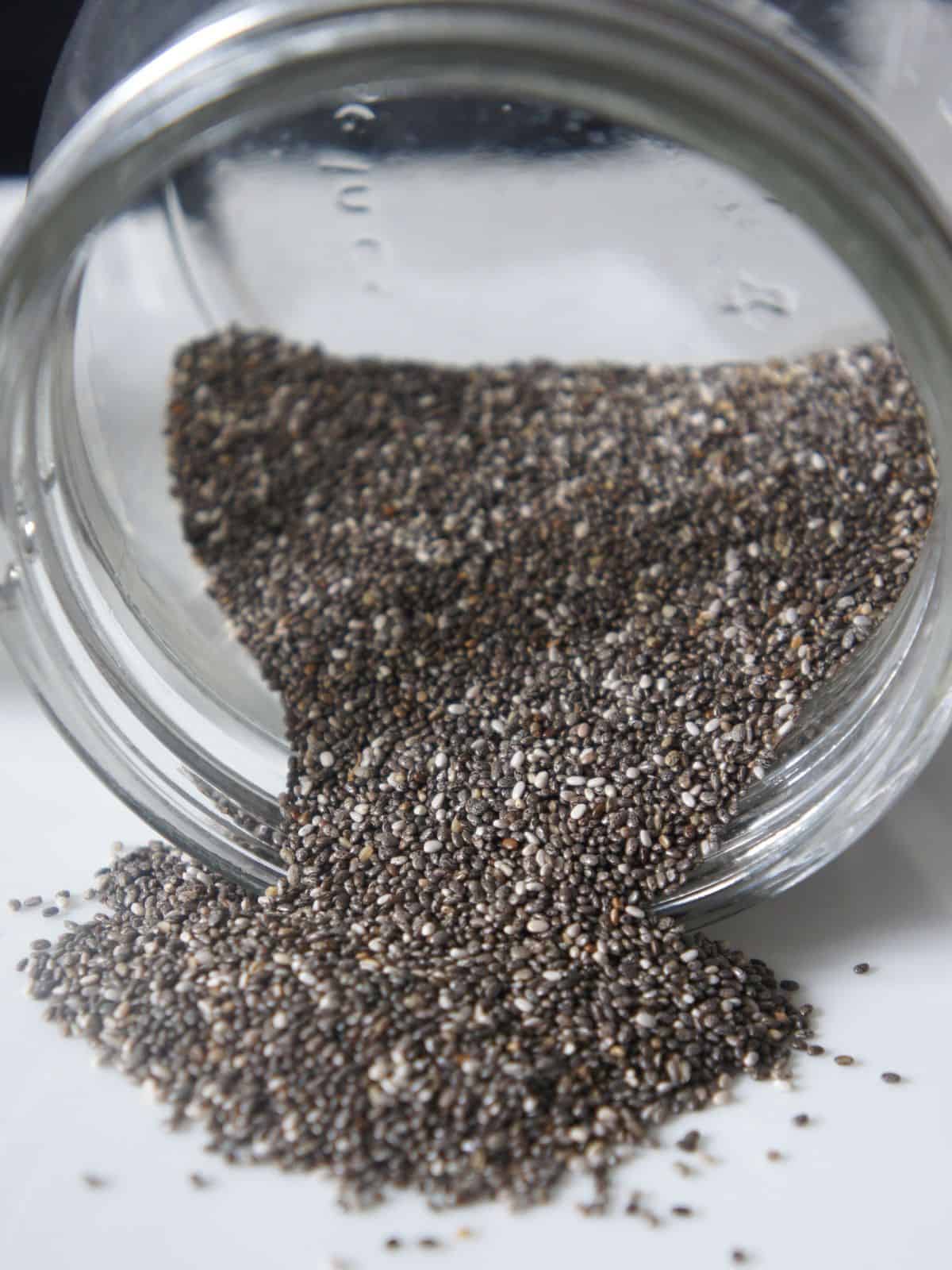 Chia seeds spilling out of glass jar. 
