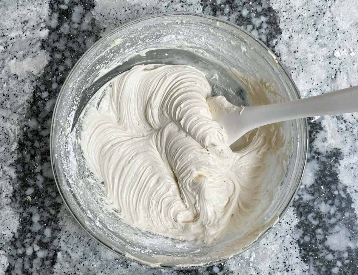 Whipped vegan cream cheese frosting in glass mixing bowl.
