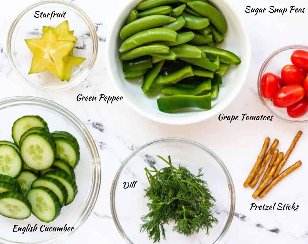 Ingredients needed for Christmas Tree Veggie Tray: pretzels, dill, cucumber, tomatoes, starfruit, green pepper, and snap peas.