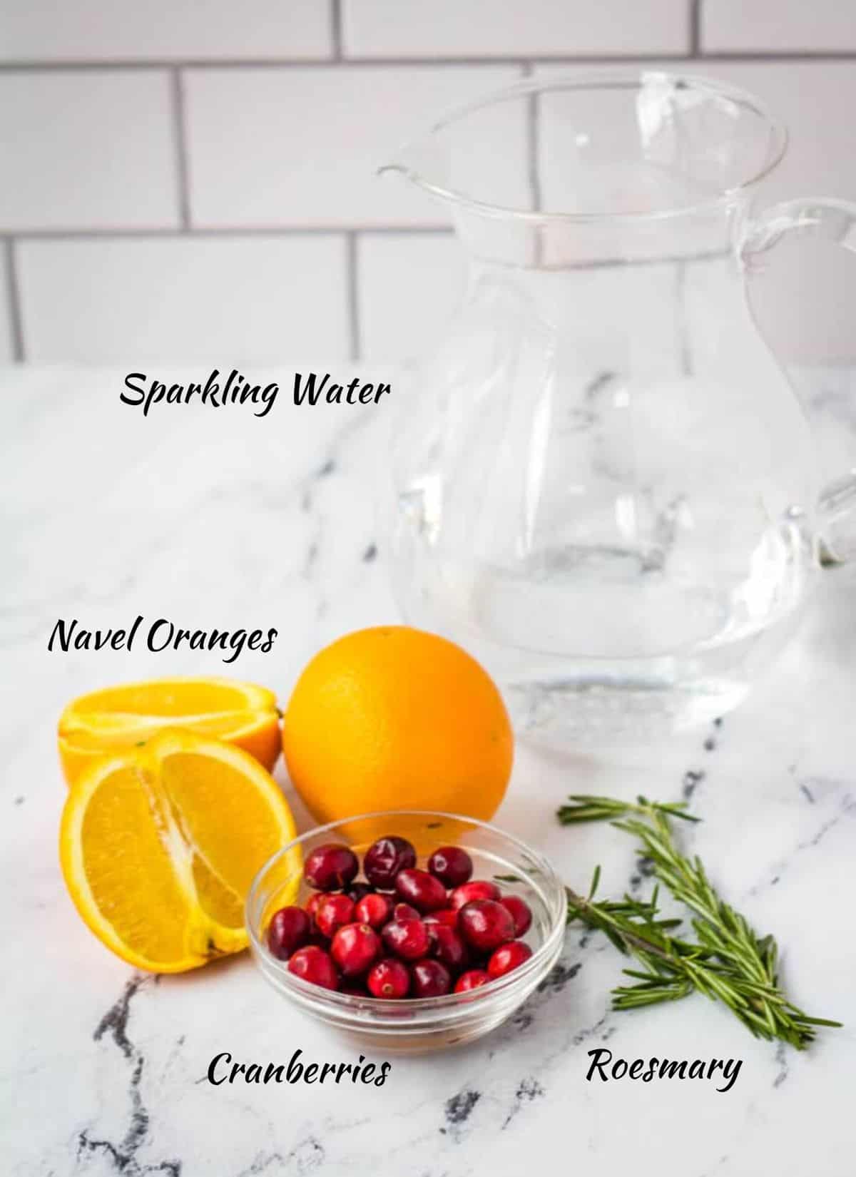 Orange mocktail ingredients: sparkling water, naval oranges, cranberries, and rosemary.