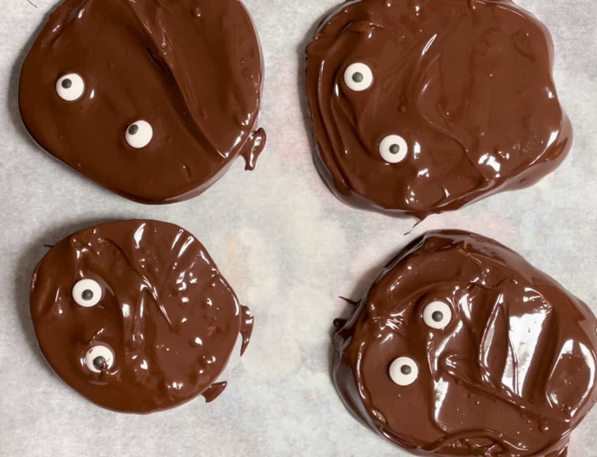 Adding candy eyes to chocolate apple slices.