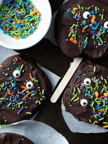Chocolate covered apple slices with candy eyes and sprinkles.