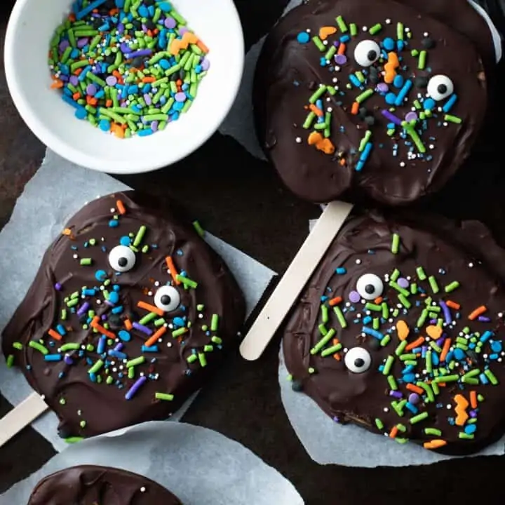 Chocolate covered apple slices with candy eyes and sprinkles.