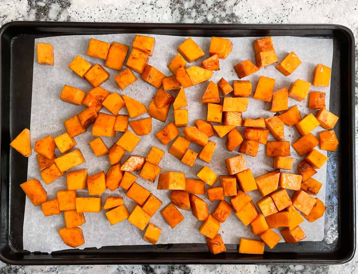 Diced butternut squash on baking sheet lined with parchment paper. 