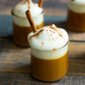Vegan pumpkin pudding with whipped cream and cinnamon stick.
