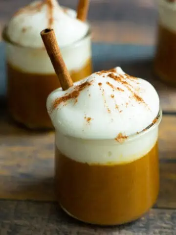 Vegan pumpkin pudding with whipped cream and cinnamon stick.