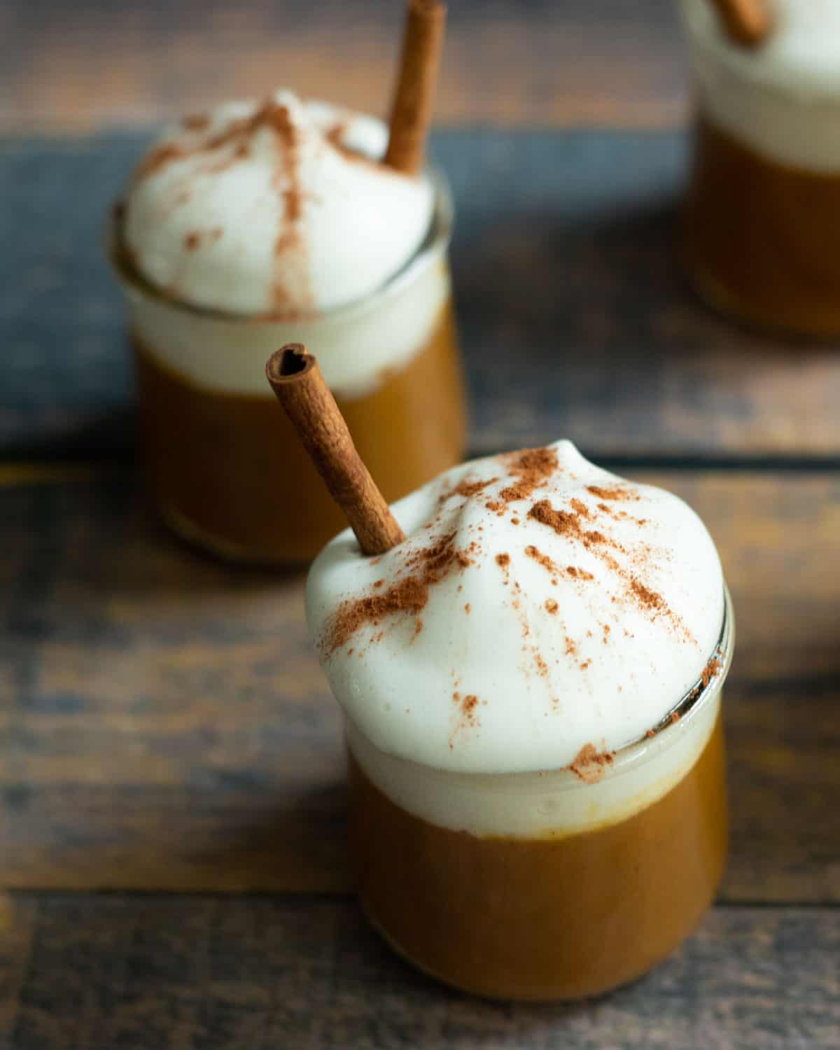 Two vegan pumpkin pudding cups topped with whipped cream. 