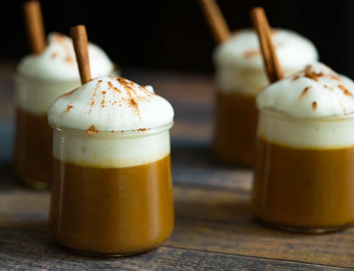 Vegan pumpkin pudding cups topped with whipped cream and a cinnamon stick. 
