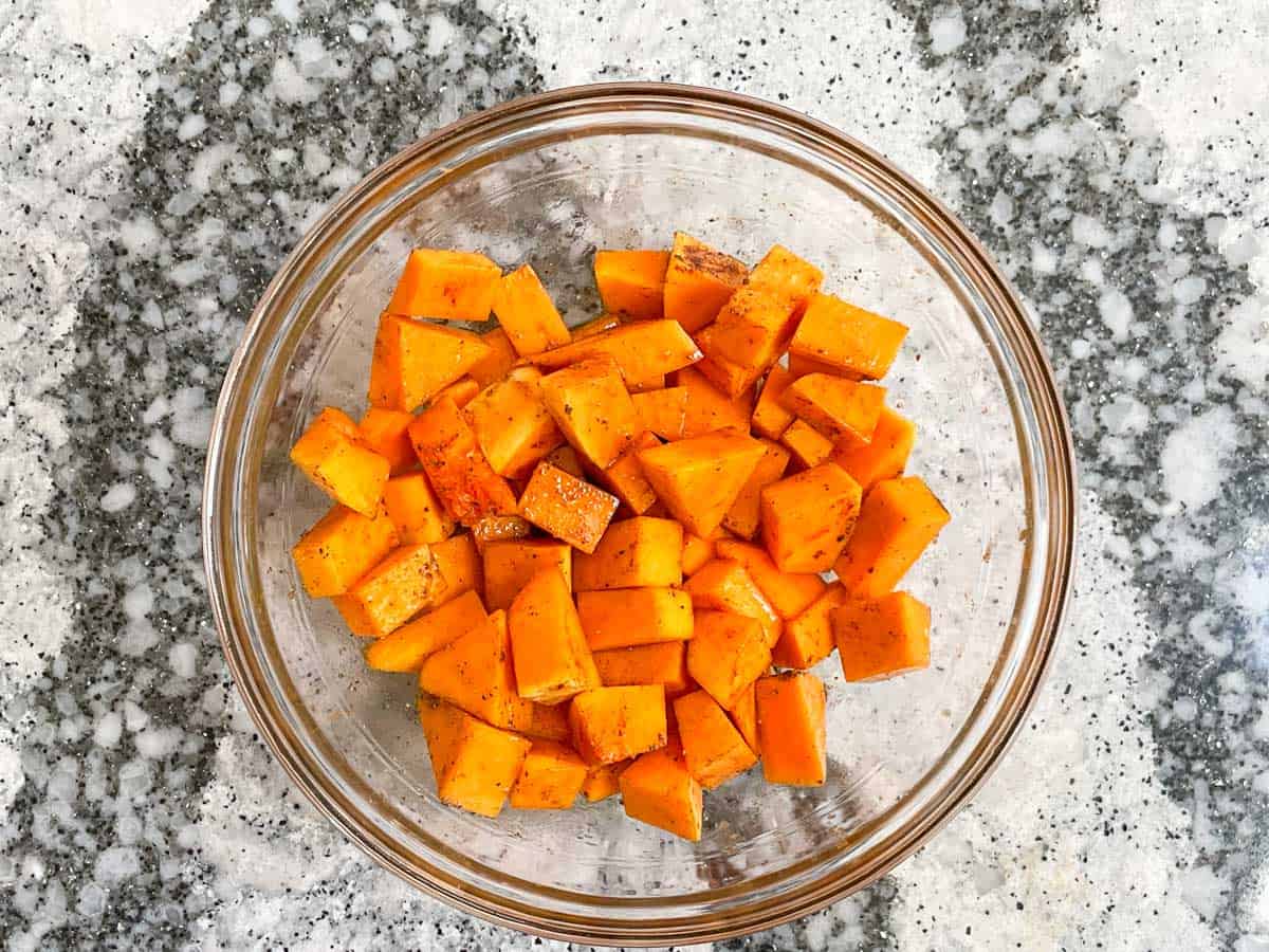Cubed butternut squash tossed with oil and spices.
