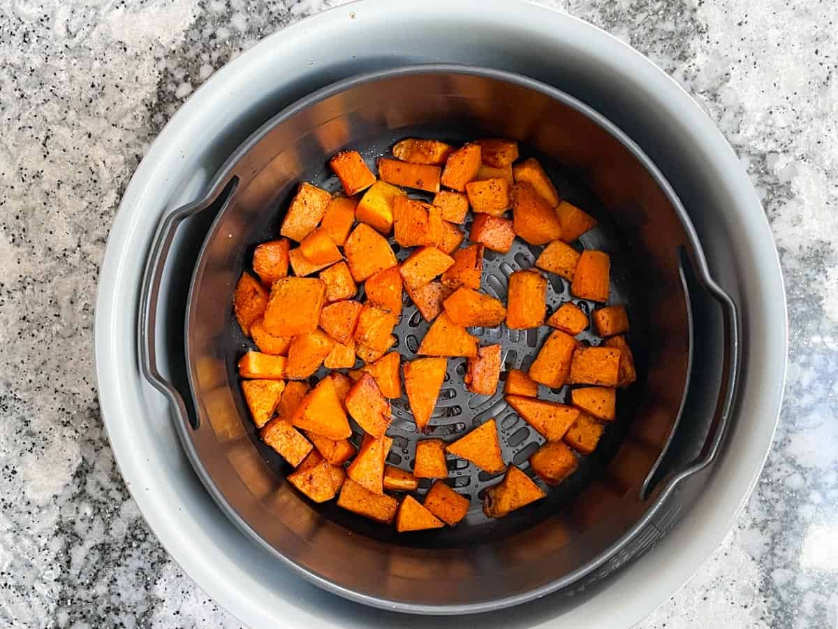 Cubed and cooked butternut squash in an air fryer basket.
