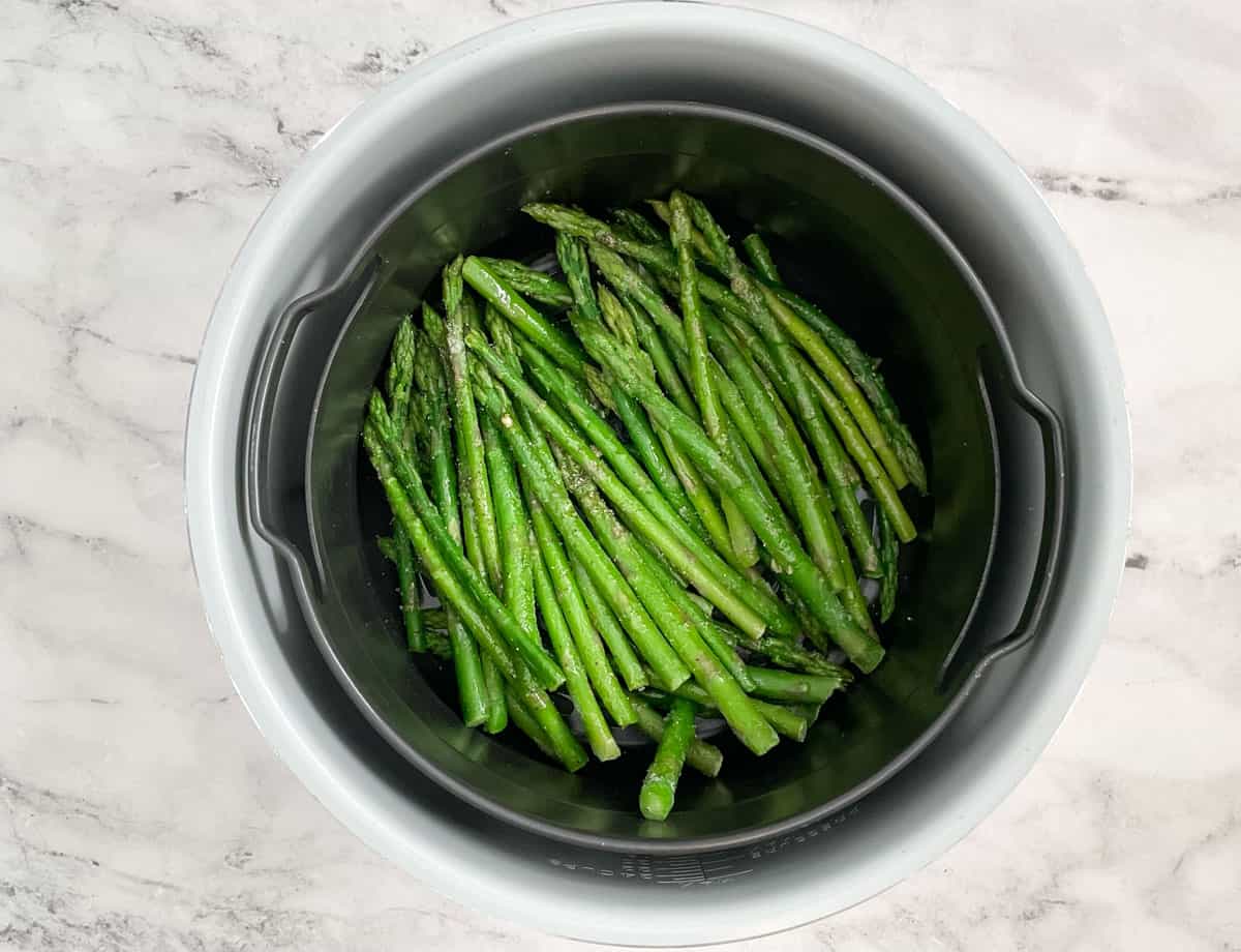Frozen asparagus in air fryer basket.
